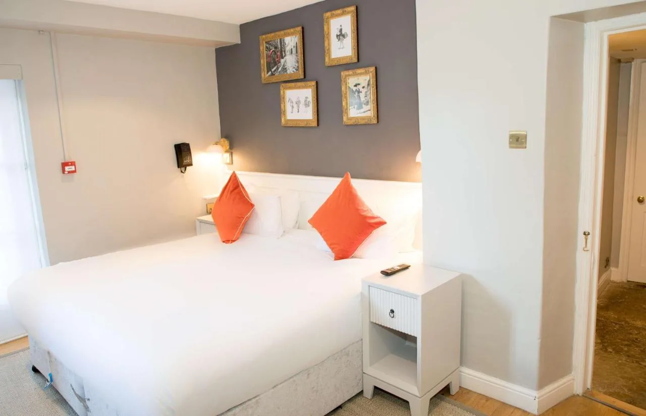a bedroom with a white bed with orange pillows at Henrietta House, a member of Radisson Individuals in Bath